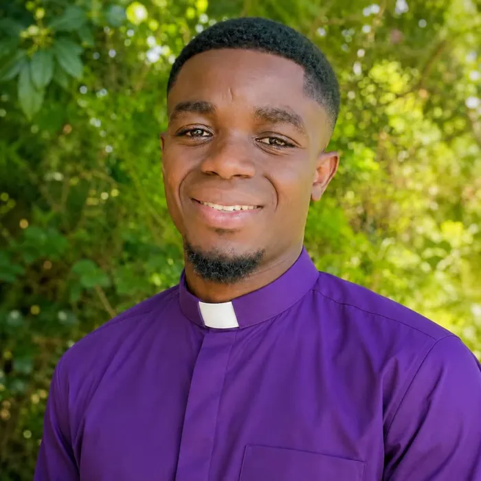 First-cohort student in purple clerical attire outdoors